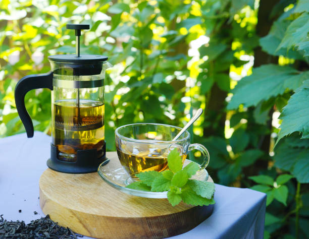 istock Teapot and a cup of tea on nature background 1327286454
