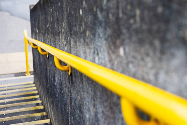 Concrete footbridge bridge over a railway line with a yellow handrail for safety