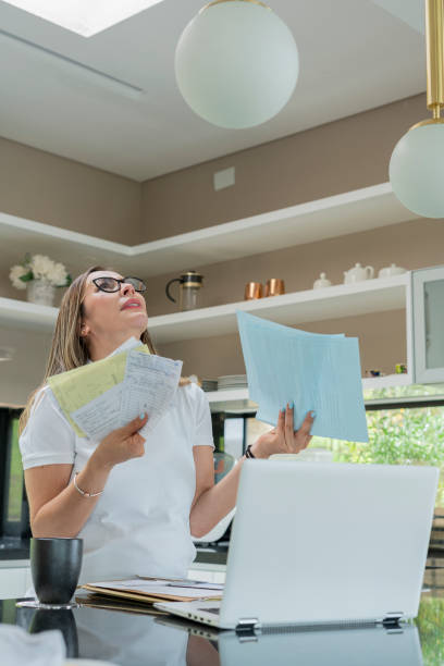 istock Woman checks her finances while using her laptop in the kitchen at home wearing comfortable clothes 1327291818