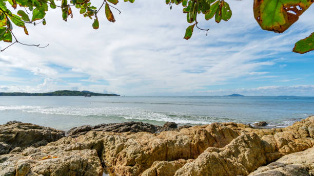 istock Rocky seashore under clear blue sky with clouds in the morning and leaves trees frame background Beautiful Sea and small island in Phuket Thailand 1327291930