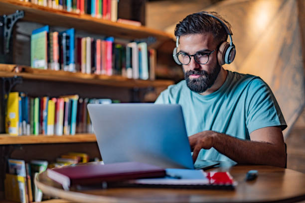 istock Male student using laptop in the library 1327295625