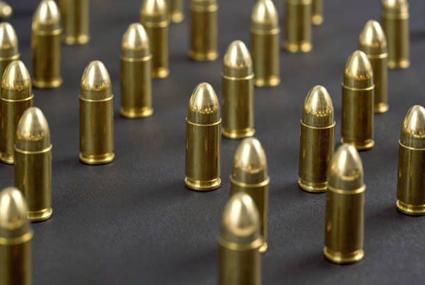 istock Yellow brass ammo bullets on black desk, arranged standing next to each other 1327295751