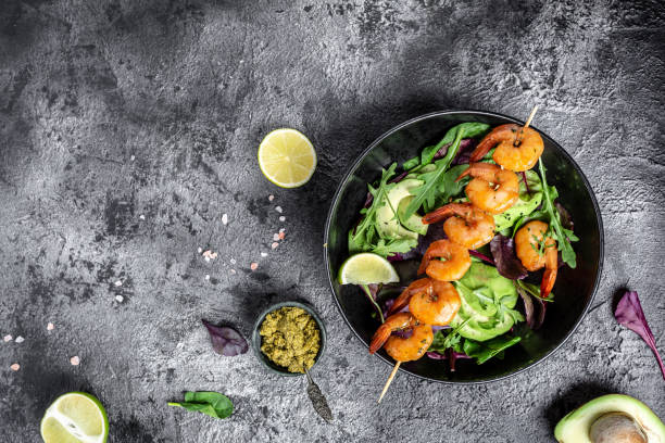 ciotola di buddha con avocado, insalata fresca, gamberi alla griglia e salsa al pesto. dieta cheto. menu ricetta posto per il testo, vista dall'alto - grilled shrimp foto e immagini stock