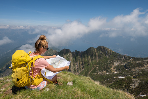 Young woman hiking looks at map for directions. 
People travel outdoors activities concept
Ticino, Switzerland