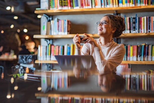 Female student have a coffee break while studying in the library stock photo
