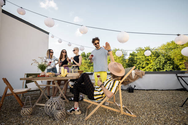 Friends chilling on the roof terrace Young group of stylish people having a festive dinner on the roof terrace. Hipsters hanging out and having great summertime together outdoors urbane stock pictures, royalty-free photos & images