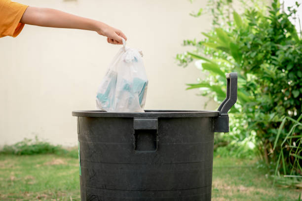 Hand of human throwing trash in plastic bags into the trash in the garden. stock photo