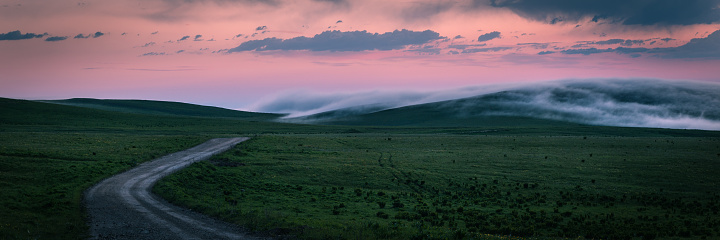 Winding road, fields, mountains, dramatic sky, Dawn. Fog, sunset