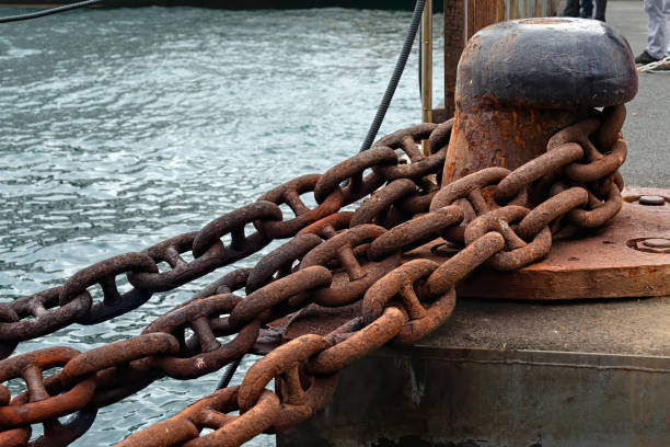 Rusty anchor chain and one headed mooring bitt Stud link type rusty ship anchor chain and one headed mooring bitt on a ferry port. mooring line stock pictures, royalty-free photos & images