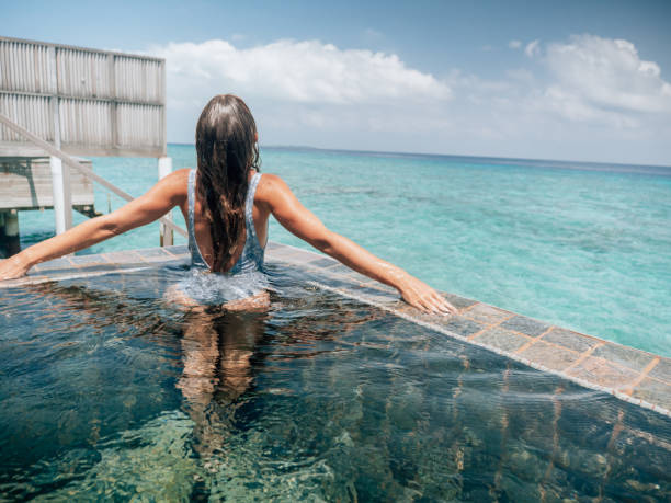 istock Woman relaxes inside infinity pool over reef lagoon 1327303187