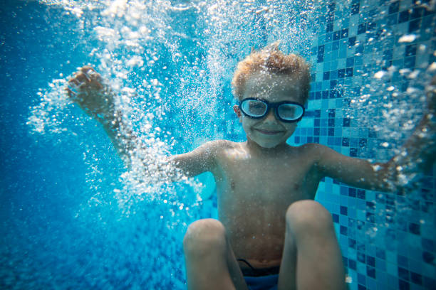 Little boy is having fun playing underwater in the resort pool.  The boy aged 6 have jumped into the pool.\nNikon D800