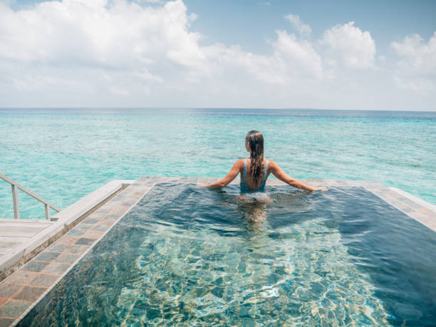 istock Woman relaxes inside infinity pool over reef lagoon 1327303871