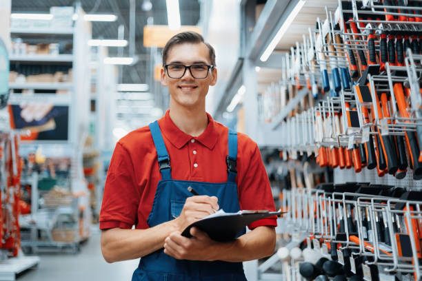 adviser in a hardware store making notes about the availability of goods on the shelves stock photo