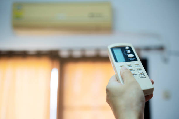 istock Hand holding remote control, adjusting temperature of air conditioner 1327305800