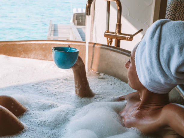 mujer joven tomando un baño en una villa de lujo sobre el mar disfrutando de una taza de café - tea women beauty pampering fotografías e imágenes de stock