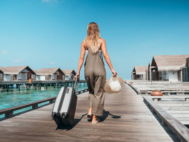 frau zieht trolley auf holzsteg in tropischem ziel - beach tourist resort one person one woman only stock-fotos und bilder