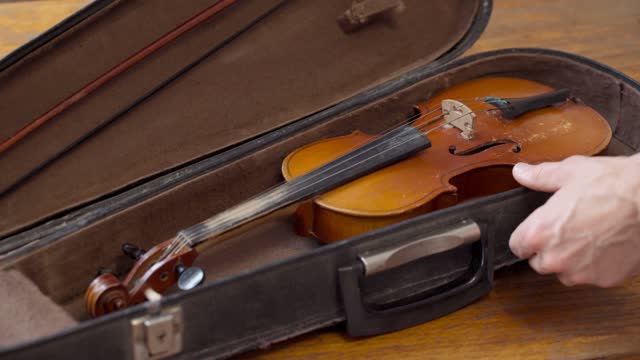 The violinist opens a case with an old retro violin. Musical mood.