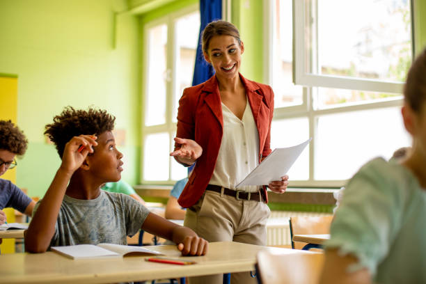 istock Young boy is sitting in classroom and talking to his teacher. 1327311716