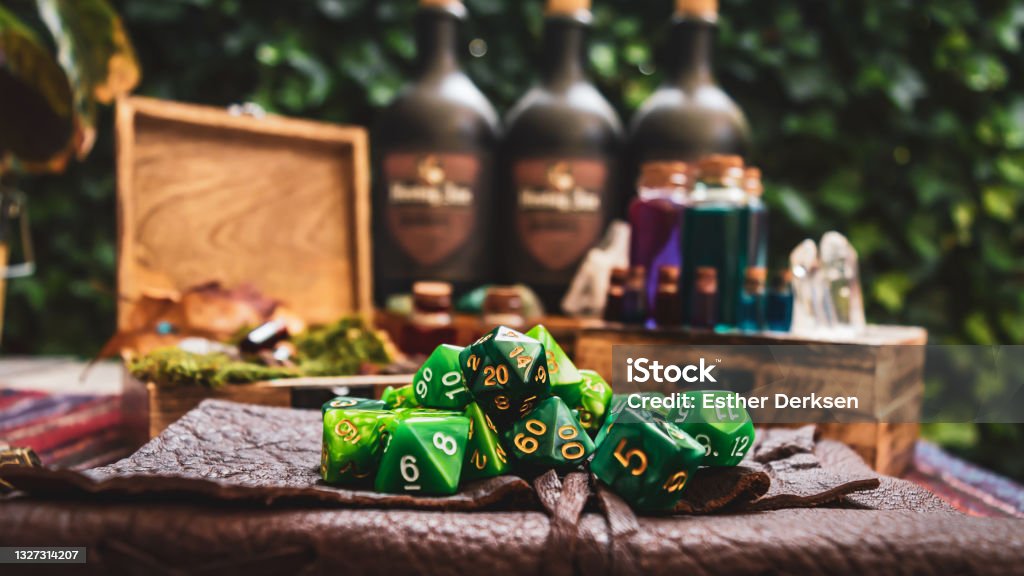a pile of green RPG gaming dice Image of a pile of green RPG gaming dice on top of a leather-bound book. Within the background wooden boxes with bottles containing a various colored liquid Role Playing Game Stock Photo