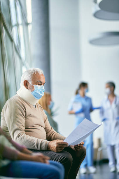 istock Senior man with neck collar reading his medical documents while waiting for doctor's appointment at clinic during coronavirus pandemic. 1327323763