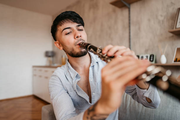istock Young man playing clarinet at home 1327325242