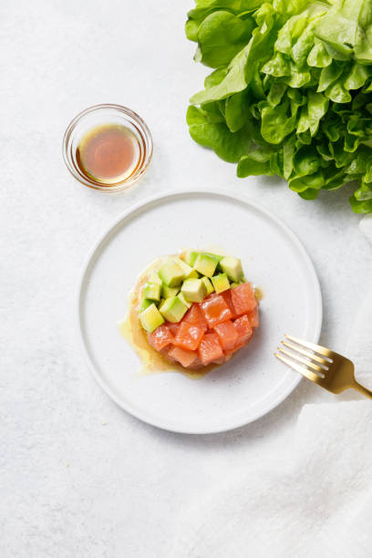istock Salmon avocado tartare with sauce on white stone table background. 1327326833