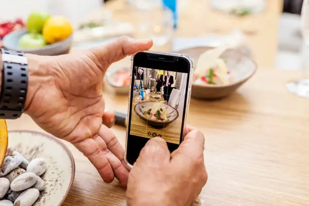 Anonymous man taking a picture with a smartphone of ceviche croaker with grenade fruit for social media and sharing with friends