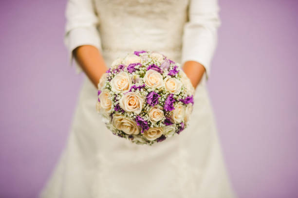 Purple and beige roses with gypsophila  wedding bouquet in hands of a bride