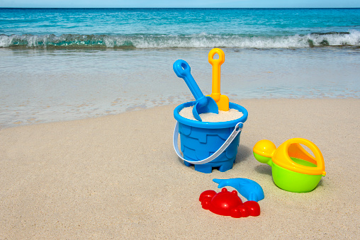 Plastic beach toys for children on a white sandy beach with a crystal clear ocean.