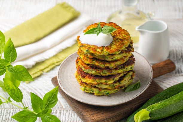 zucchini-fritter werden mit basilikum und griechischem joghurt serviert. sommermahlzeit. - frittiertes gebäck stock-fotos und bilder