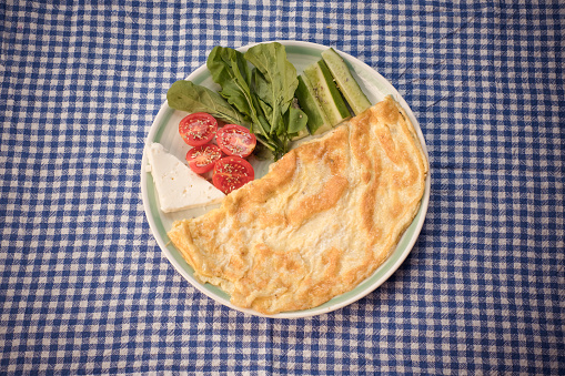 A folded omelets served with herbs and tomatoes