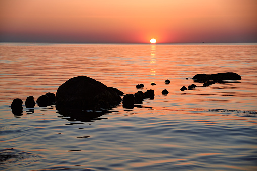 Beautiful sunset at the Baltic Sea. Rows of old wooden breakwaters with stones