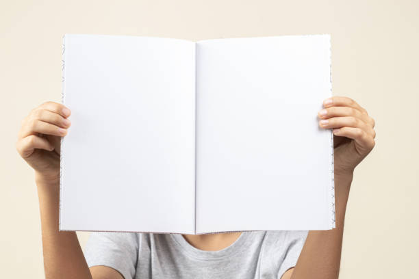 istock Kid hands holding open notebook with blank white pages in front of him 1327347937