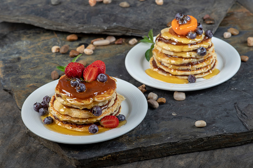 Pancakes cascaded on top of each other with a nut filling.\nTop with honey and caramel sauce garnished with strawberries, blueberries and apricot.