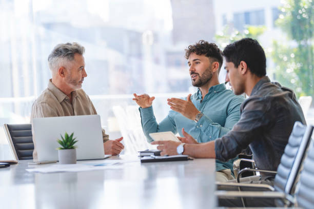 istock Three businessmen meeting at a board room table 1327351697