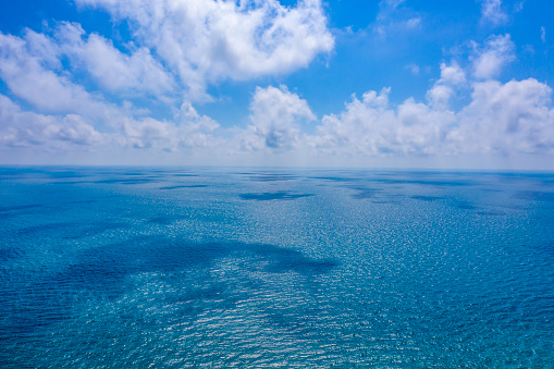 Aerial view against the backdrop of blue sea water and sun reflections. Aerial view of a flying drone. Waves water surface texture. Aerial photography.
