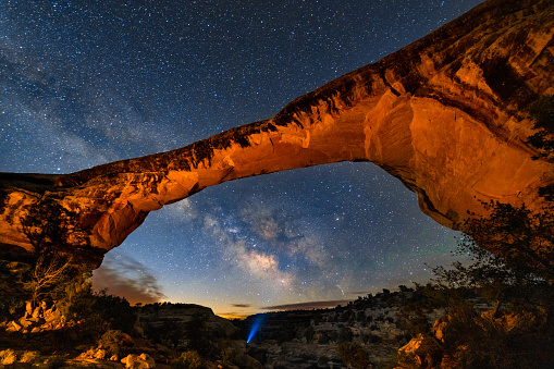 Red Rock Arch with Headlamp Beam Projecting to Milky Way - Night astrophotography landscape in natural arch setting. Desert Southwest USA.