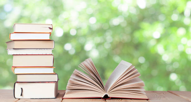 Open book with stack of books on the wood table