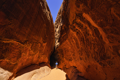 Man Hiker Hiking in Narrow Slot Canyon - Beautiful red rock scenic sandstone canyons with man walking through canyon.