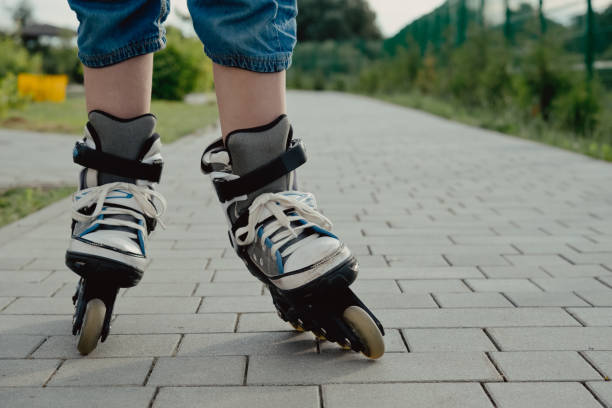 istock Little boy in protective equipment and rollers stands on walkway in park, low angle view 1327356240