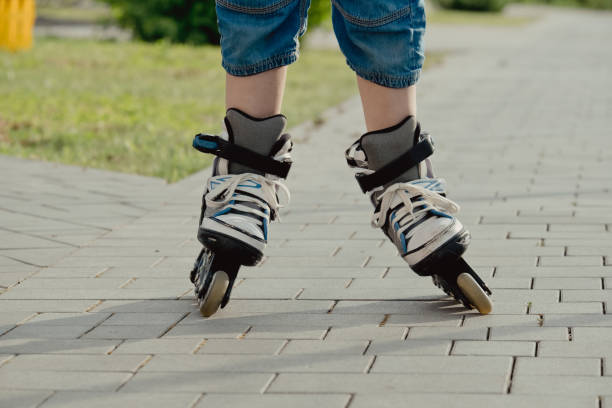 istock Little boy in protective equipment and rollers stands on walkway in park, low angle view 1327356285