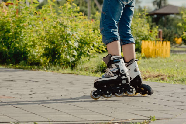 istock Little boy in protective equipment and rollers stands on walkway in park, low angle view 1327356293