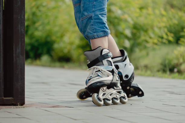 istock Little boy in protective equipment and rollers stands on walkway in park, low angle view 1327356868