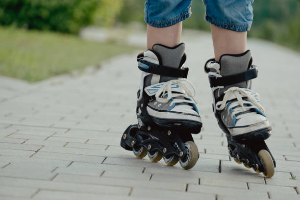 istock Little boy in protective equipment and rollers stands on walkway in park, low angle view 1327356875