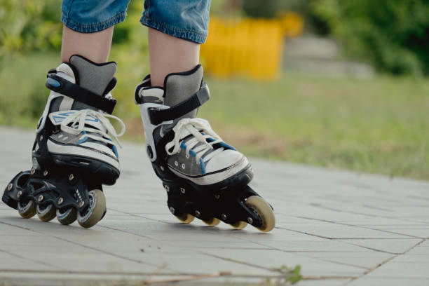 istock Little boy in protective equipment and rollers stands on walkway in park, low angle view 1327356912