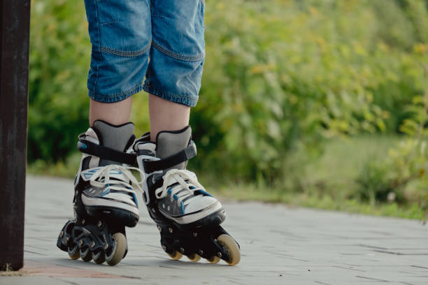 istock Little boy in protective equipment and rollers stands on walkway in park, low angle view 1327356950