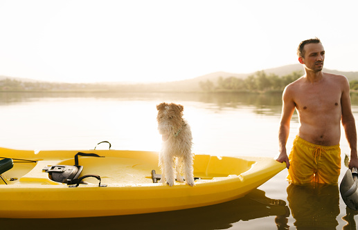 Photo of a young man and his dog kayaking on the lake, on a hot summer afternoon, far from the city hustle.