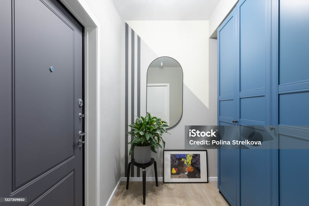 Entrance hallway in a modern design apartment: grey and white walls, built-in wardrobe. Safety home, high-quality front door Front Door Stock Photo