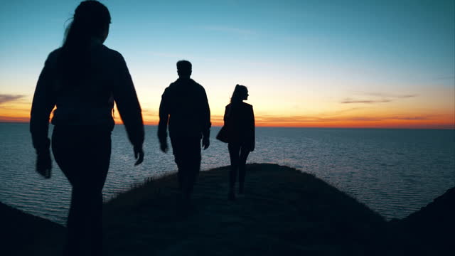 The three people walking on the mountain against the seascape