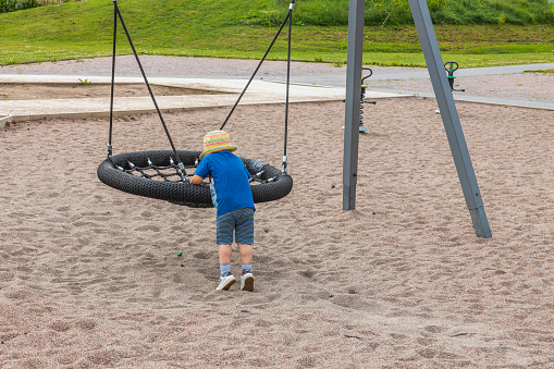 Boy on a swing and girl in the background on a children's playground